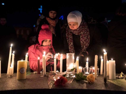 Sawsan Idris, right, lights candles with her daughters Lara (left) and Tamara while attending a vigil in Moncton, N.B. on Jan. 30, 2017 for the victims of the shooting.