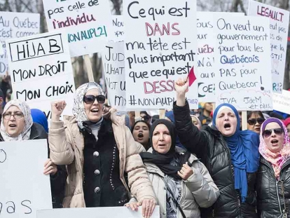 People hold up signs during a demonstration in Montreal in opposition to the Quebec government’s newly tabled Bill 21.